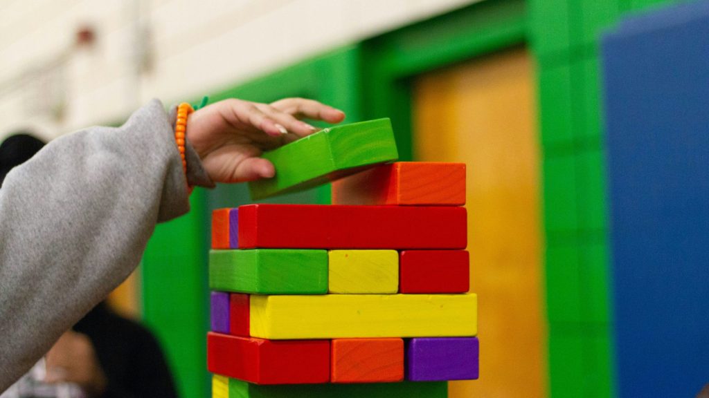 A child's arm plays with colorful building blocks